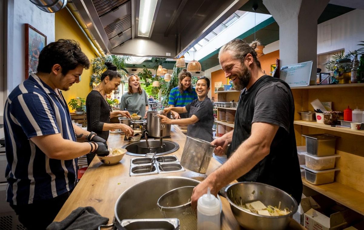 Catering-Event in der Regenzeit: Gruppe von Gästen beim gemeinsamen Kochen